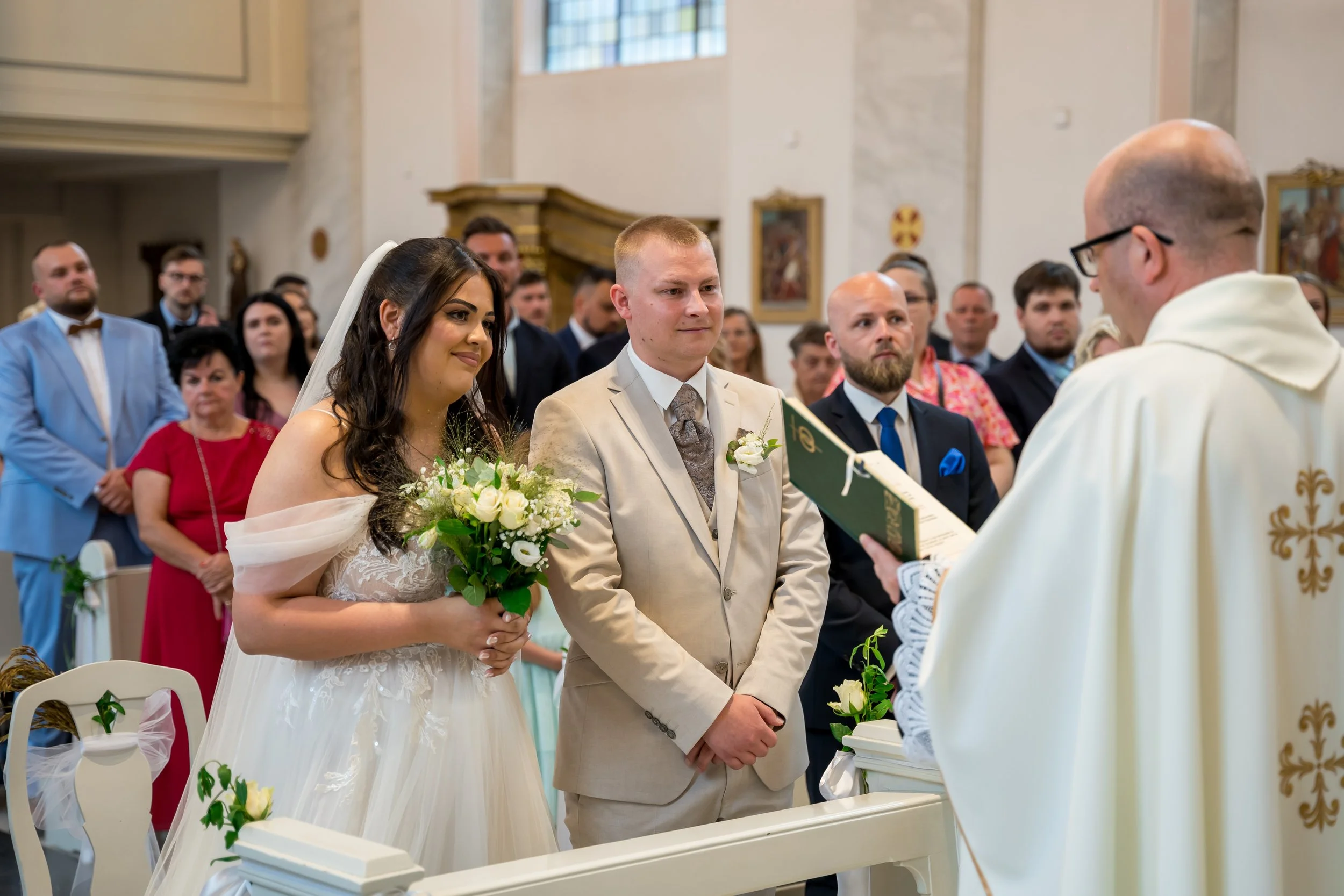 Braut und Bräutigam bei der Trauung in der Kirche, umgeben von Gästen.