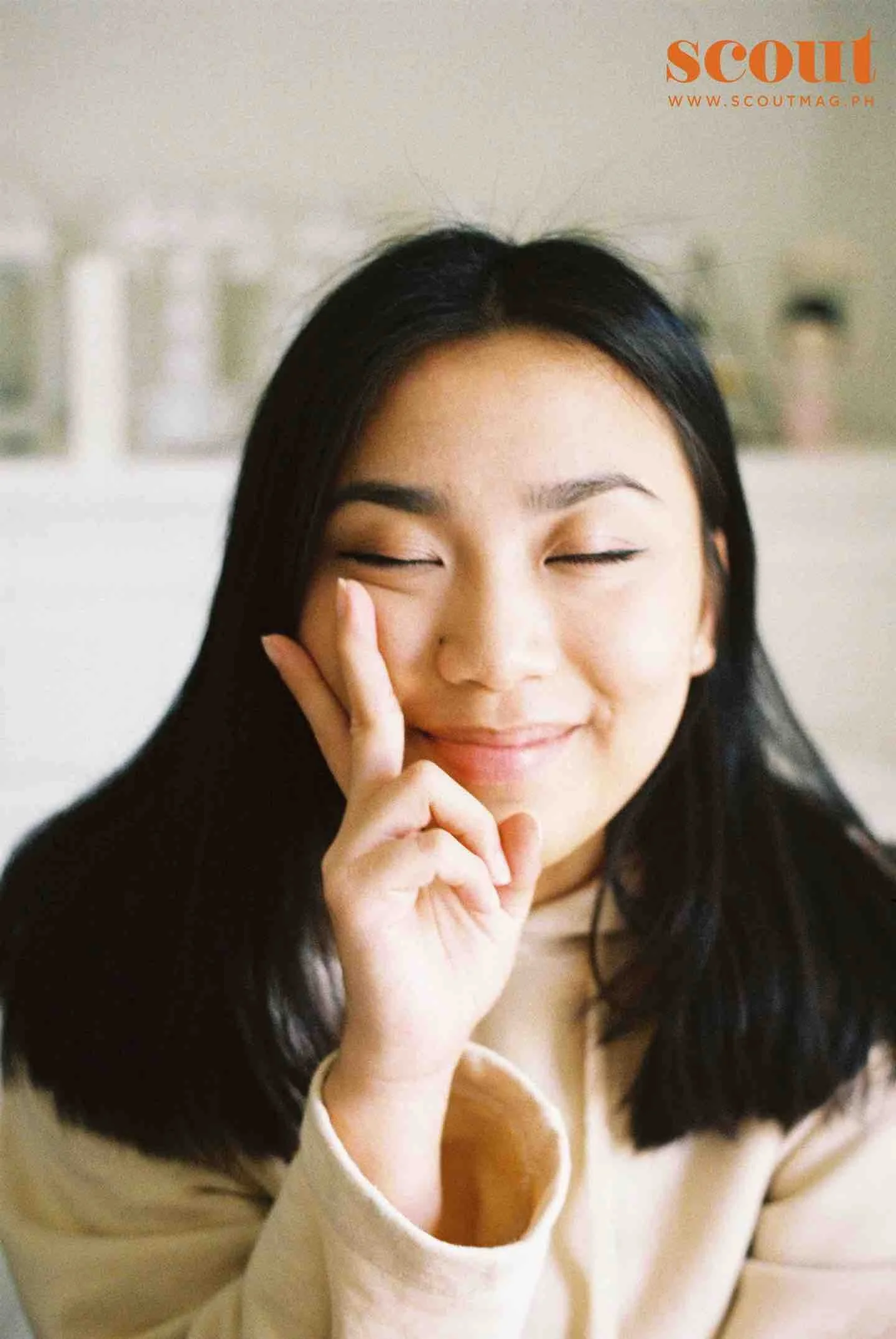 Tala Gil smiling with closed eyes, touching her face with her hand in a relaxed pose.
