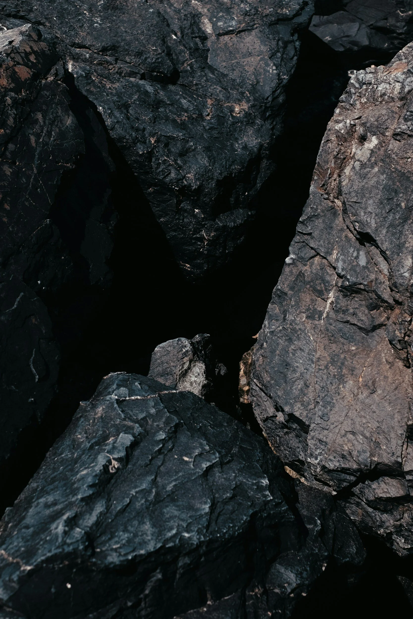 Close-up of black rocks with a crevice in the middle.