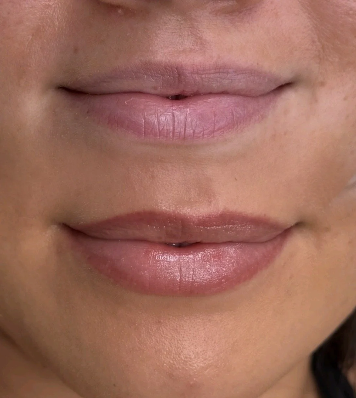 Close-up of a woman's lips with natural pink color, showing smooth skin and subtle shine.
