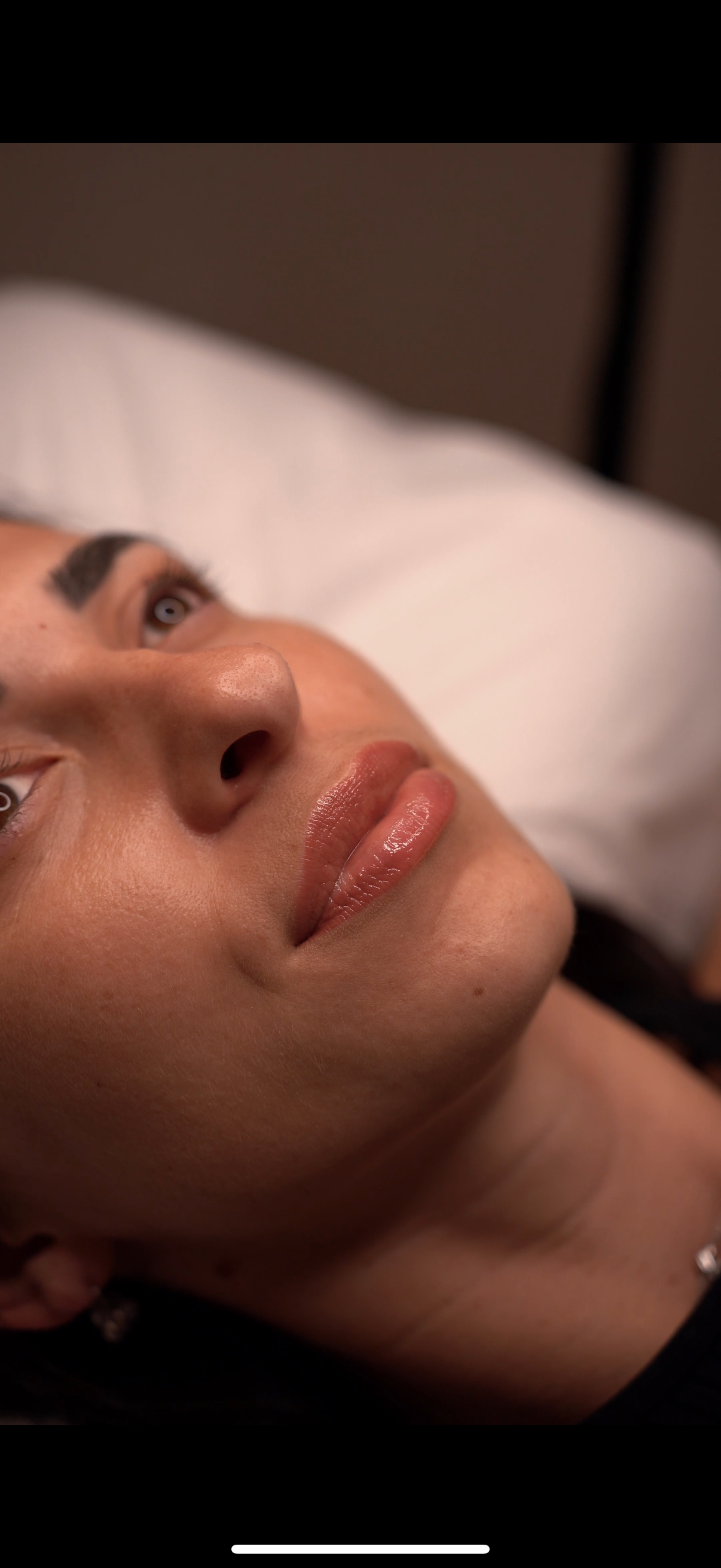 Close-up of a woman's face lying down, showing her lips, nose, and eyes looking upwards.