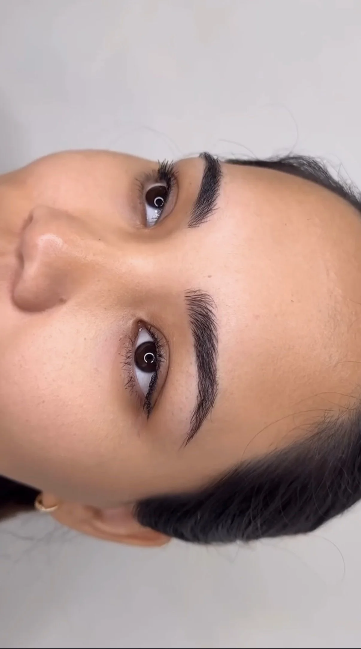 Close-up of a woman's face showing her well-groomed eyebrows, brown eyes, and smooth skin.