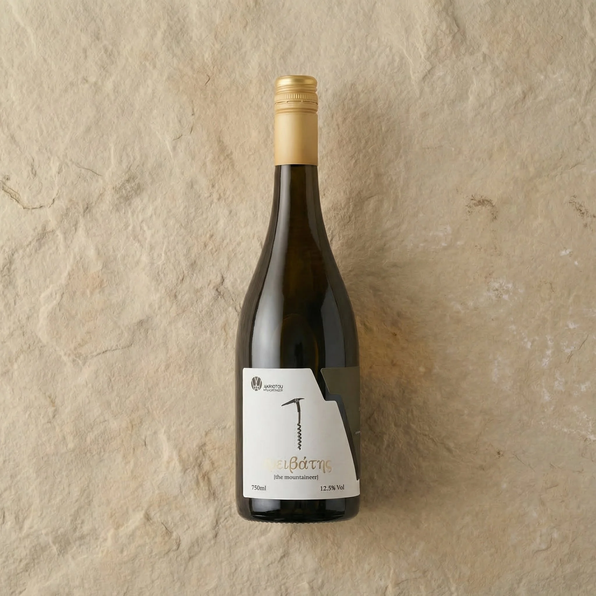 A dark green wine bottle with a gold cap and a white label, placed on a beige stone surface.