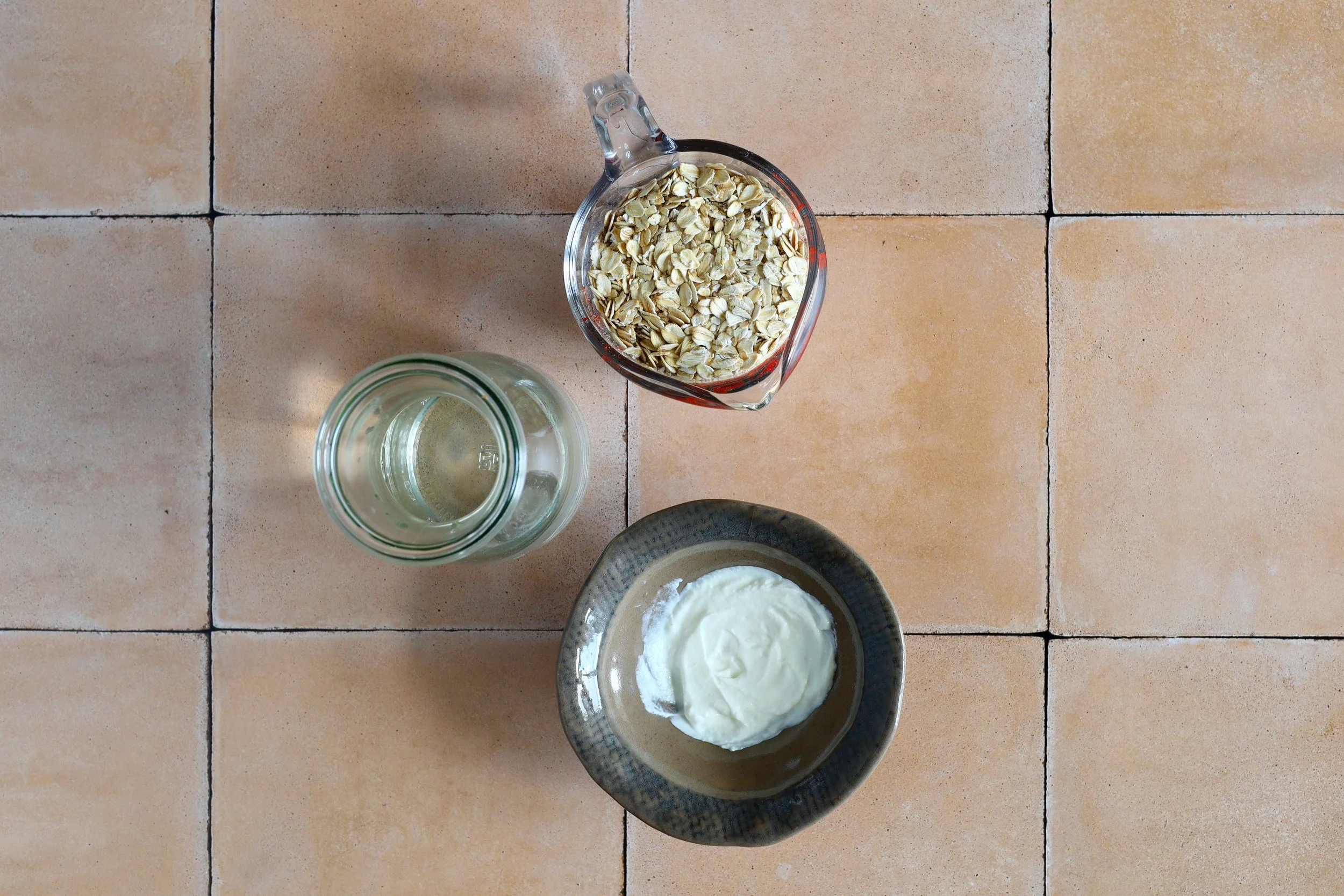 Eine Schüssel Joghurt mit einer Tasse Haferflocken und einer Tasse Wasser daneben