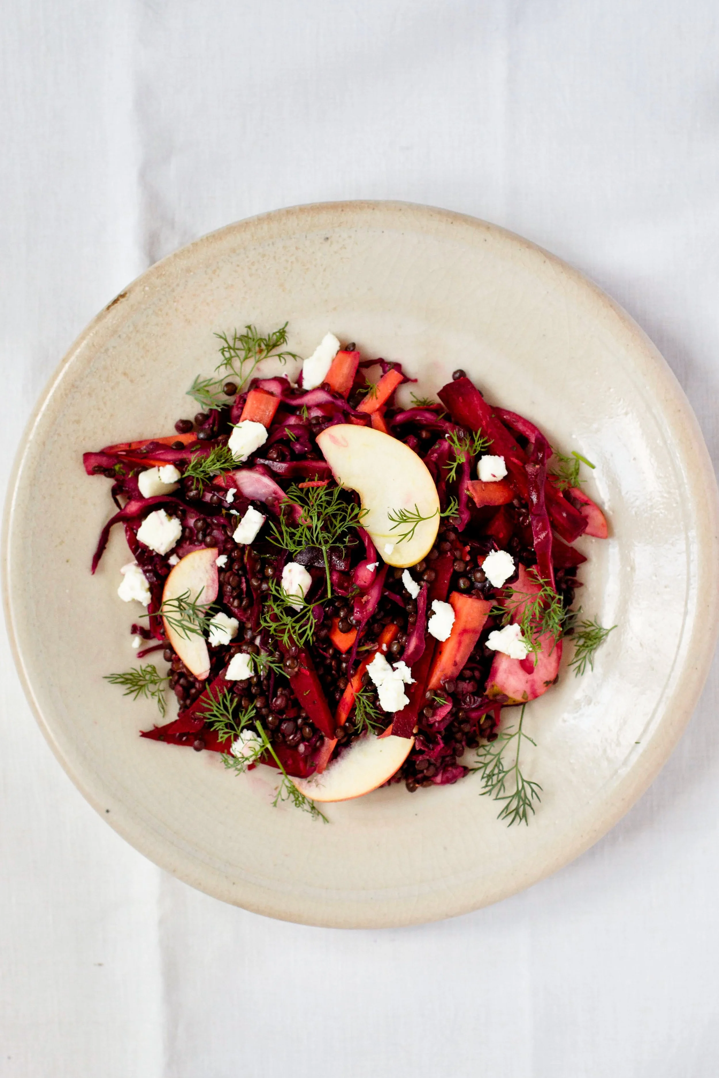 Tangy Winter Veggie Lentil Salad in bowl on white tablecloth