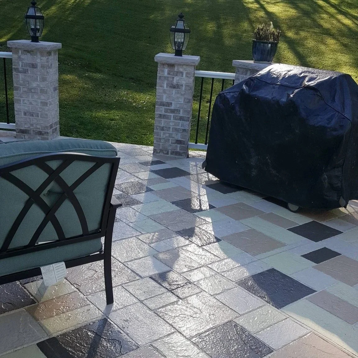 Sunlit outdoor patio with a grill, patio, brick, stone  pillars and a grassy yard, colored concrete, stamped concrete, design