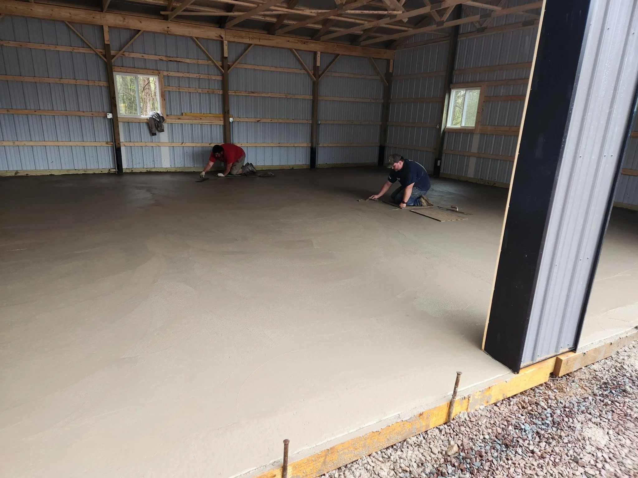 Two workers smoothing concrete floor inside polebarn, garage floor, insulated, drainage, cut floor, expansion joint. workspace, cars