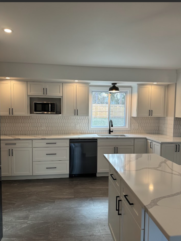 Modern kitchen with white cabinets, a hexagon tile backsplash, a black faucet, a window, and a white marble countertop island.