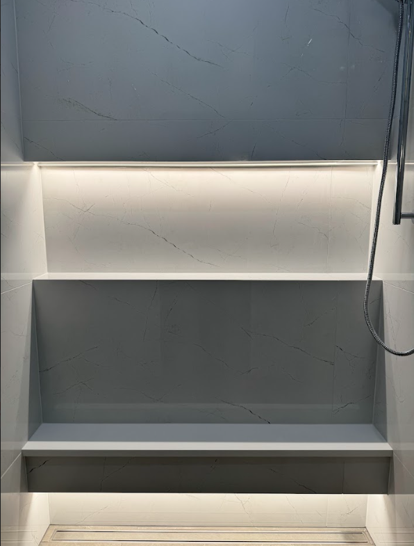 Modern shower area with gray marble tiles and built-in lighting.