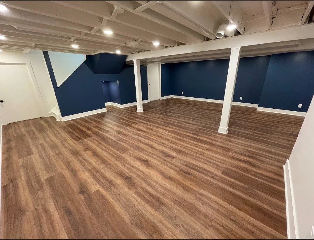 Empty room with wood flooring, blue and white walls, and white ceiling with recessed lighting.