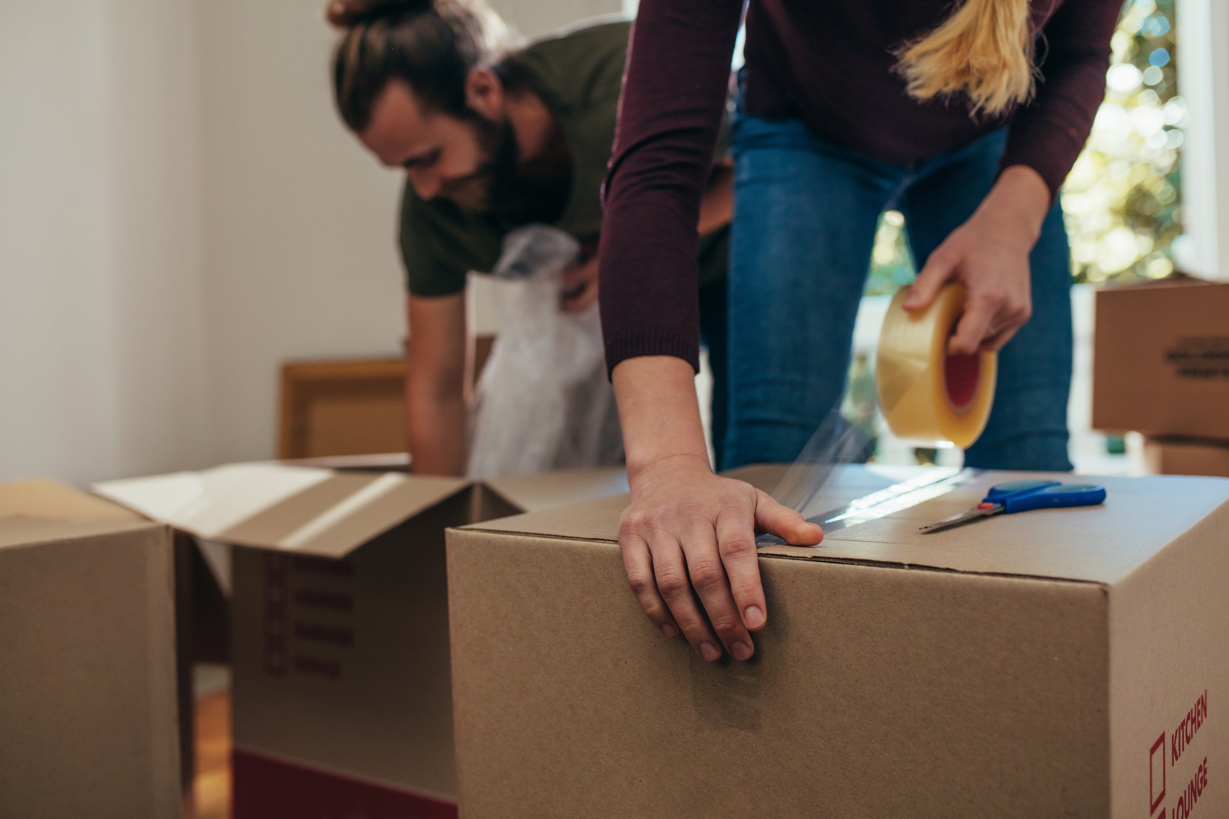 Person sealing a moving box during a home packing and organizing session.