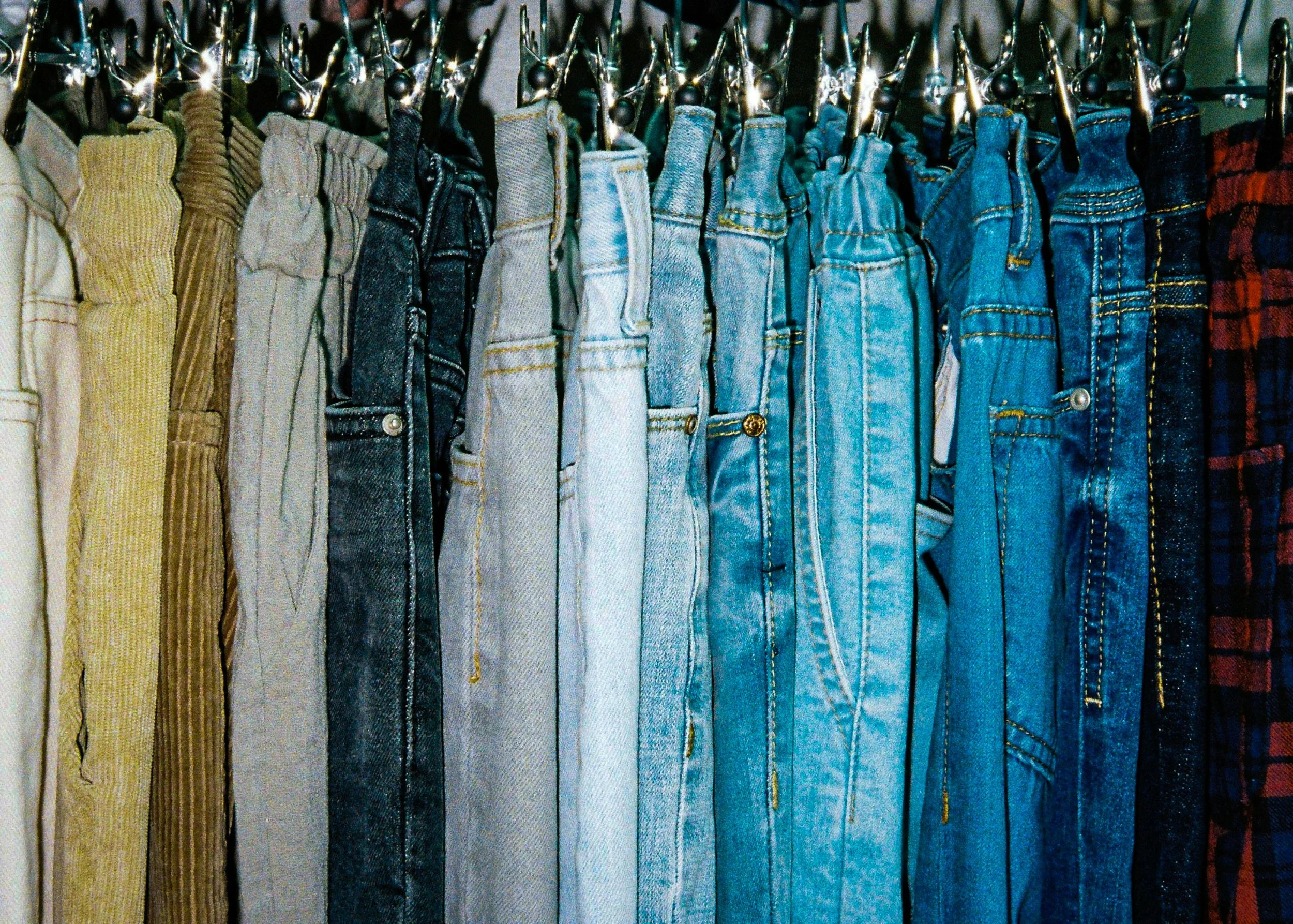 Neatly hung denim jeans on closet hangers as part of an organized wardrobe system.
