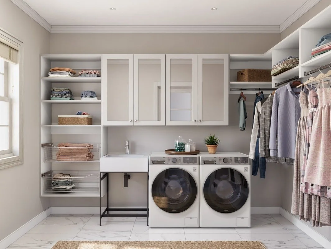 Laundry room with white cabinets, washing machine, dryer, a sink, and shelves with folded clothes and storage baskets.