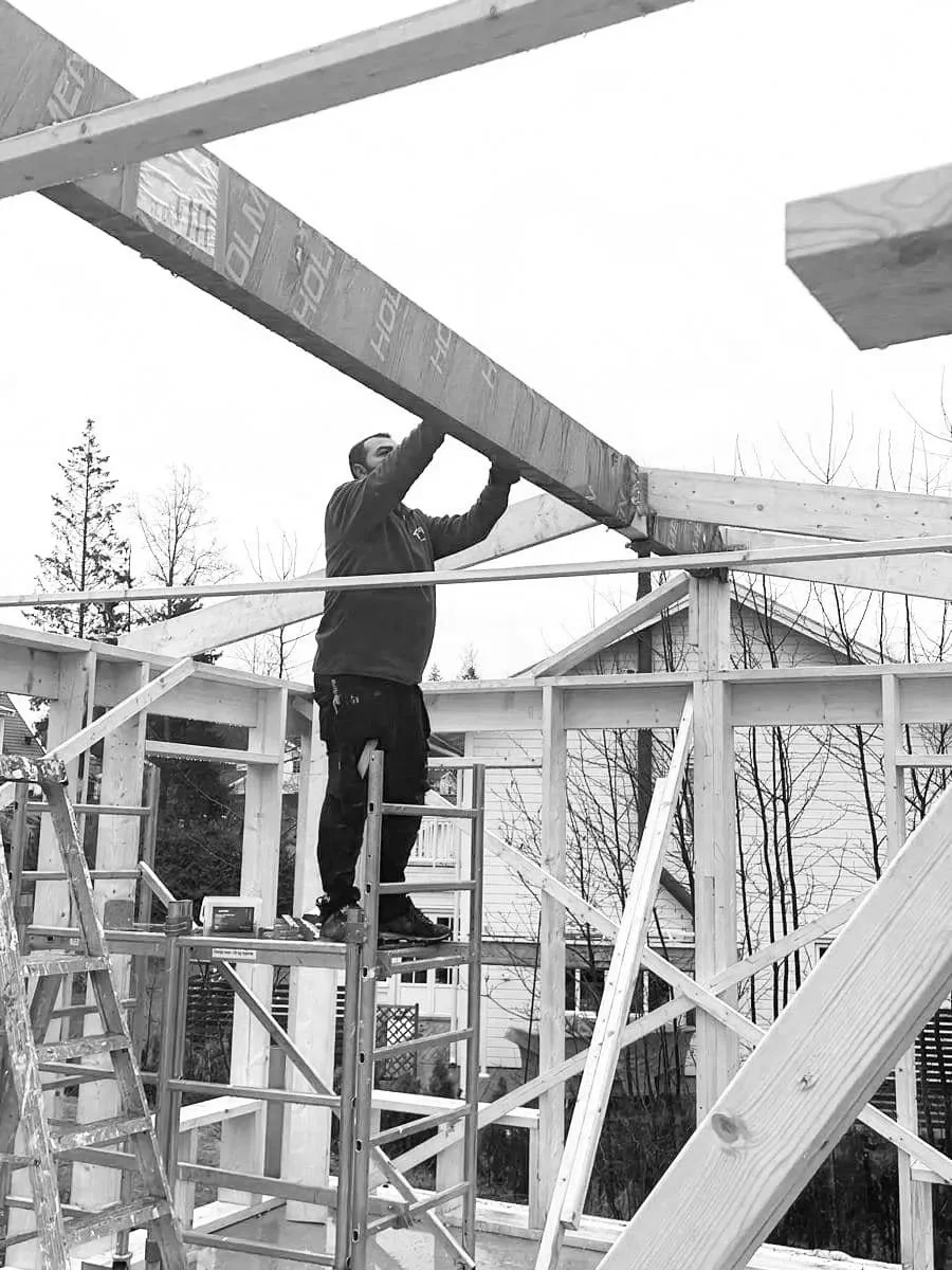 Man som bygger ett träramverk med hjälp av en arbetsplattform, det är ett bygge i ett bostadsområde.