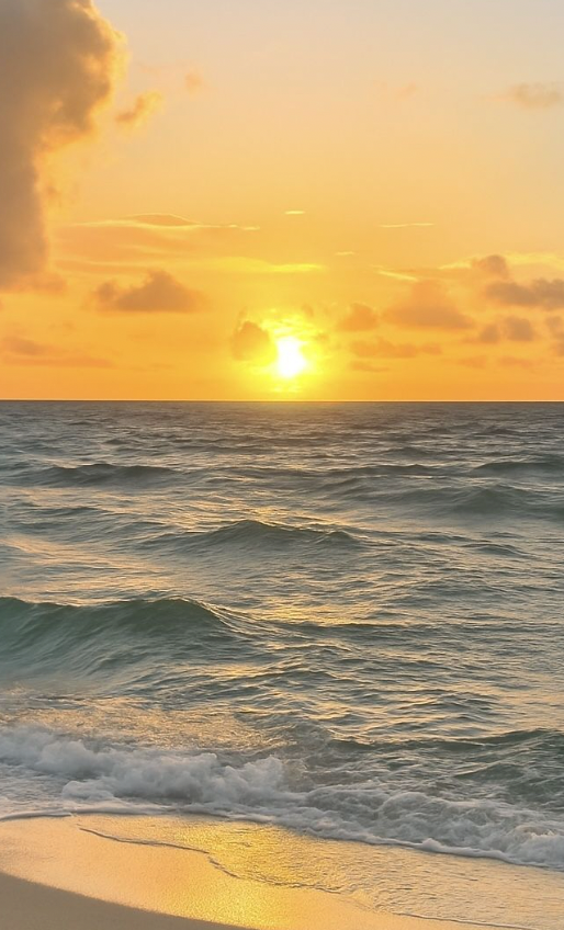 Sunset over the ocean with waves crashing on the sandy beach, golden clouds in the sky.