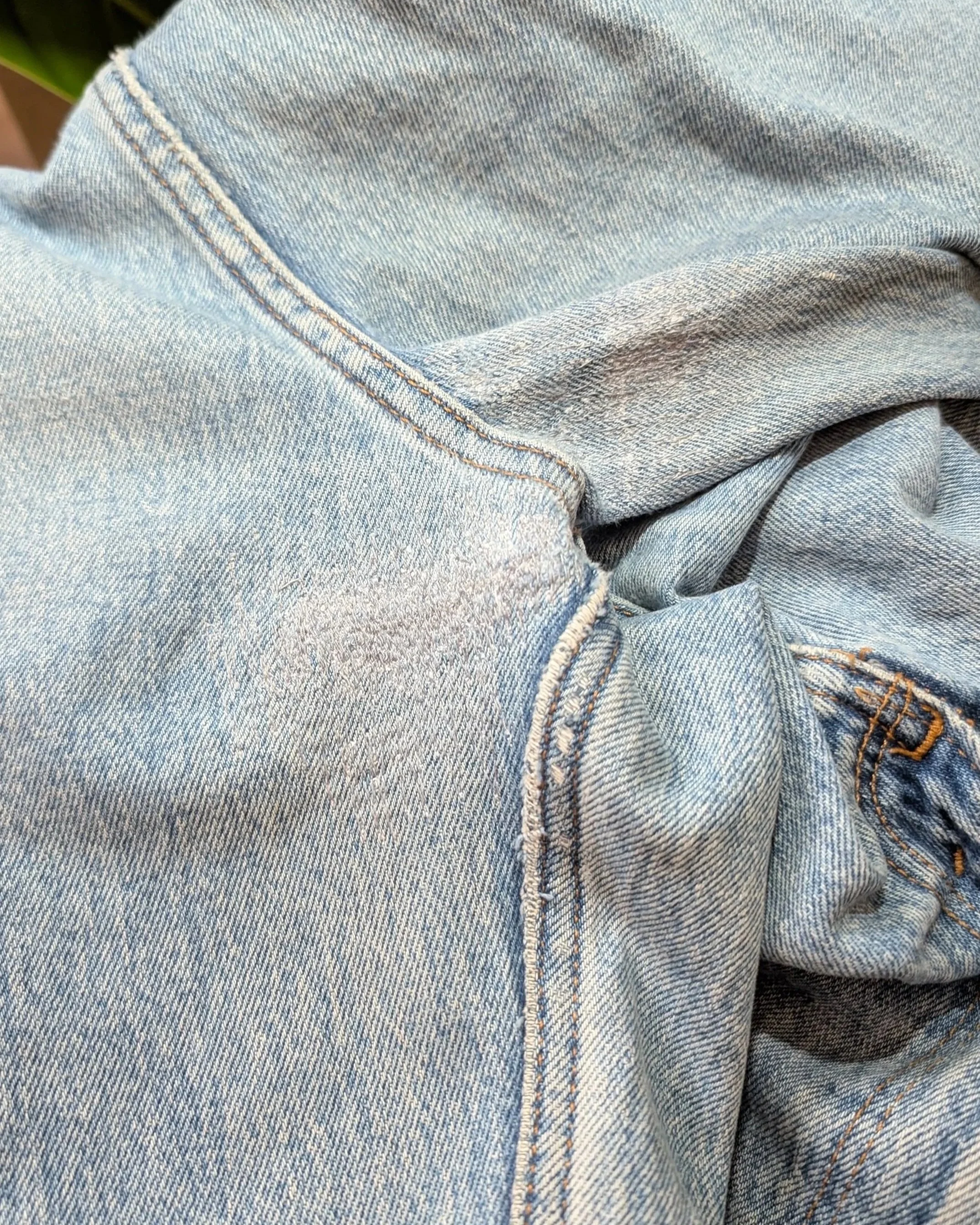 Close-up of light blue denim jeans with visible stitching and folds.