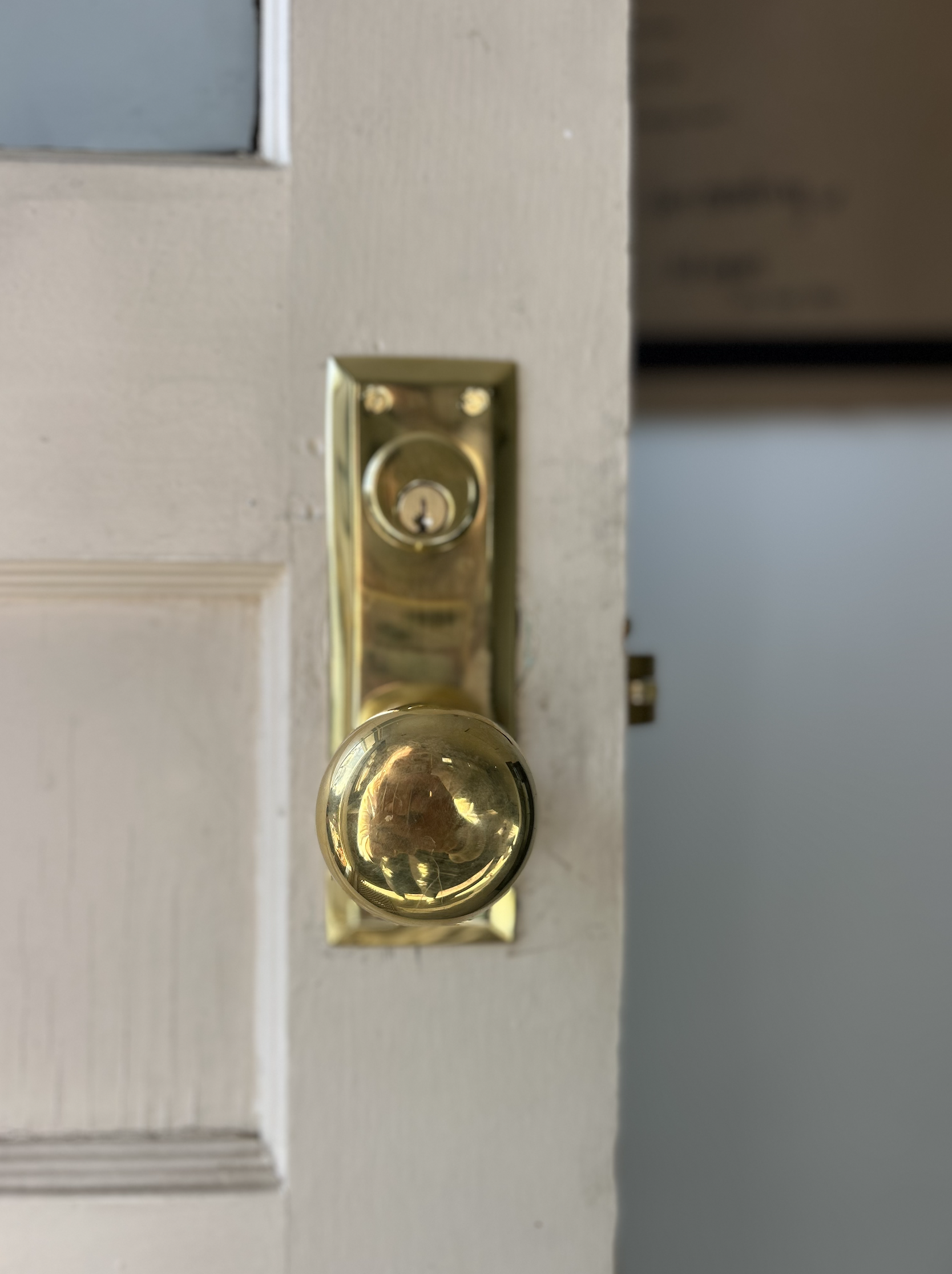 Close-up of a brass door handle and lock on a white door.