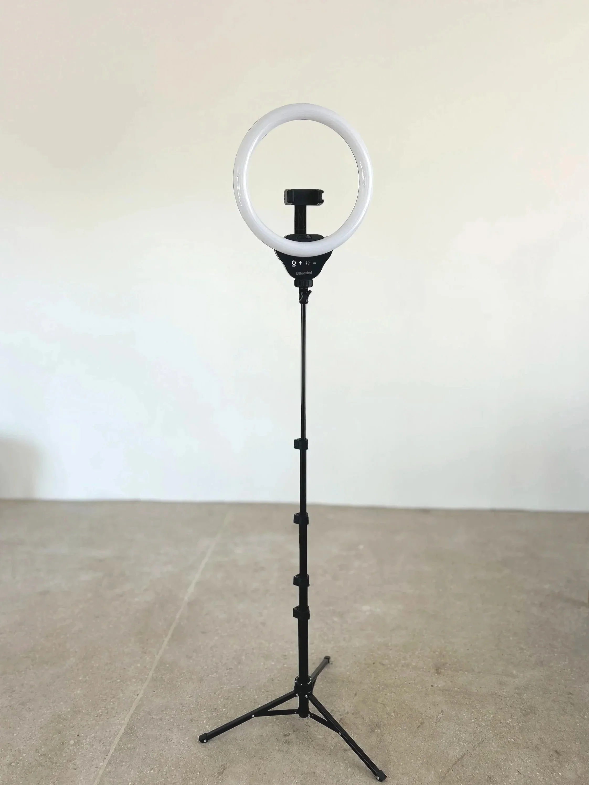 A ring light with a smartphone holder on a tripod stand.