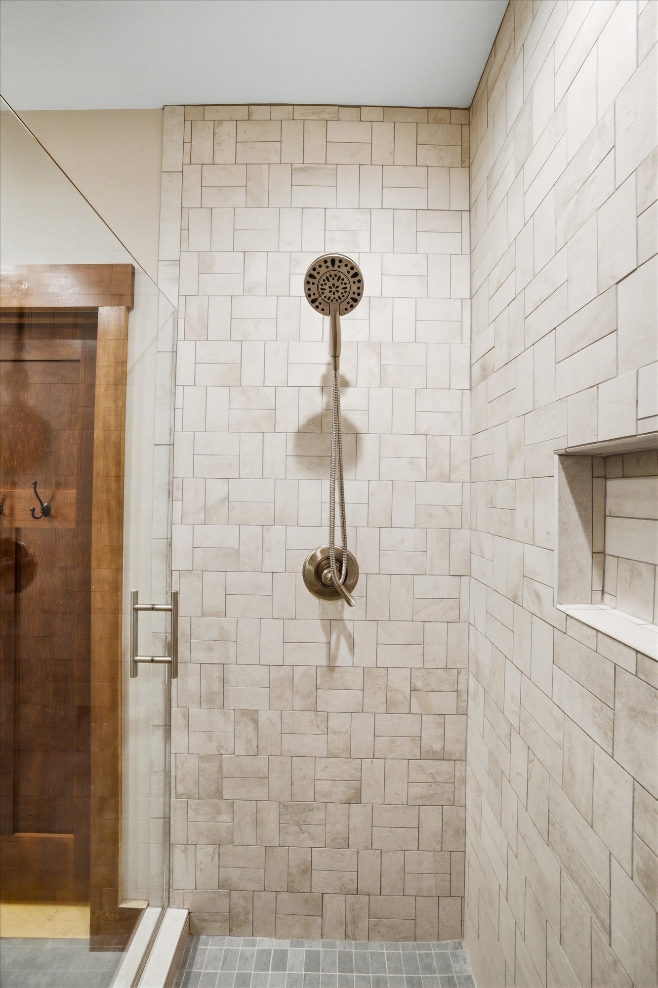 Shower area with beige tile walls, a round showerhead, and a built-in niche.