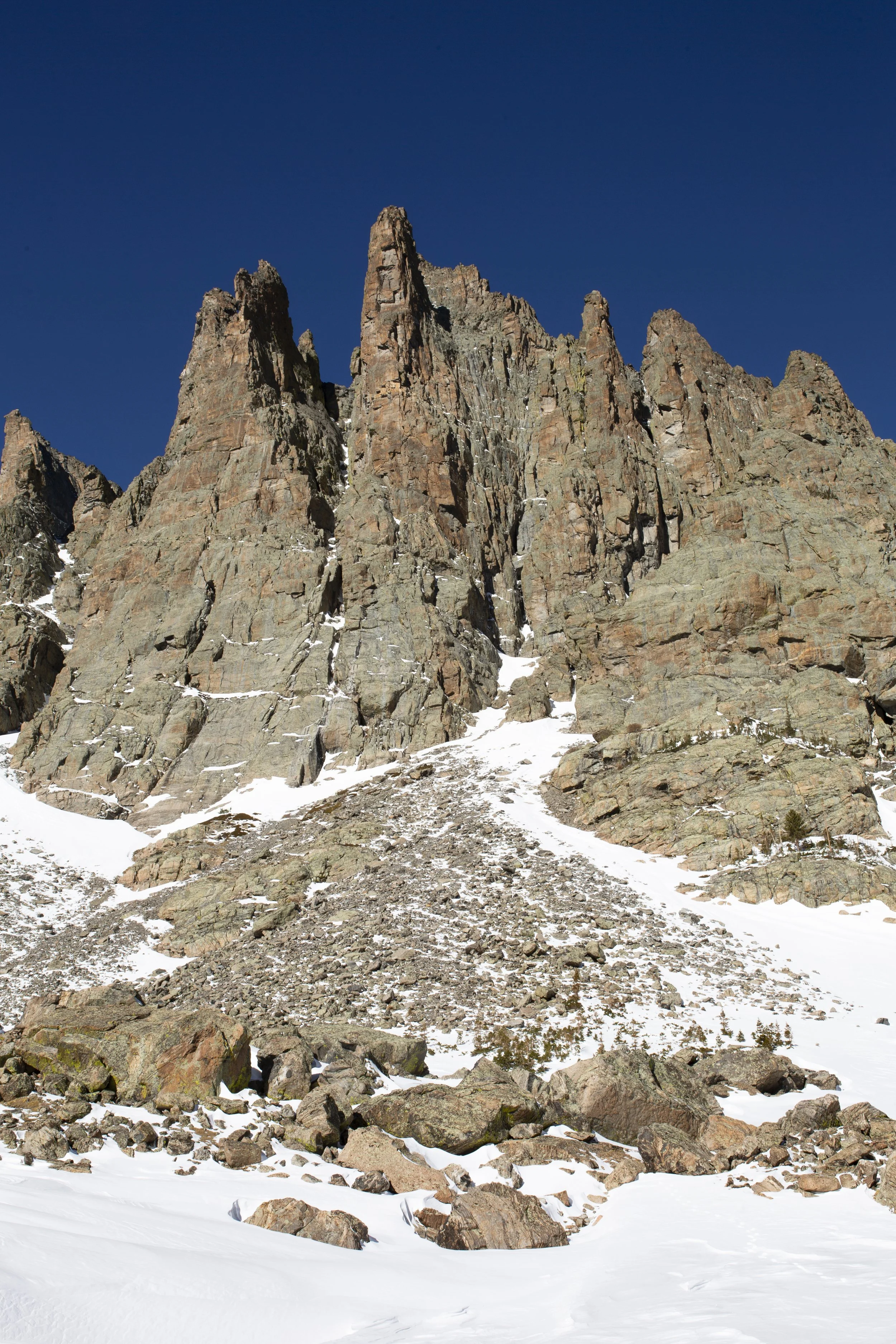 Snow-covered mountain peaks and rocky terrain under a clear blue sky.