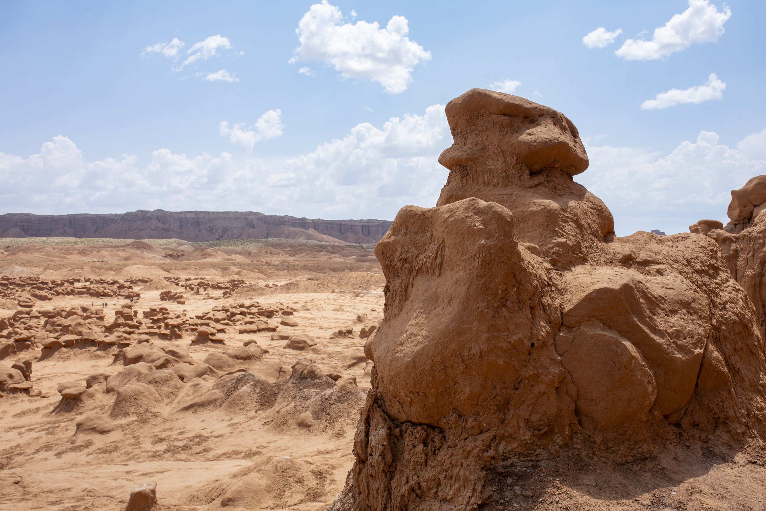 A desert landscape with large red rocks and a blue sky with scattered clouds.