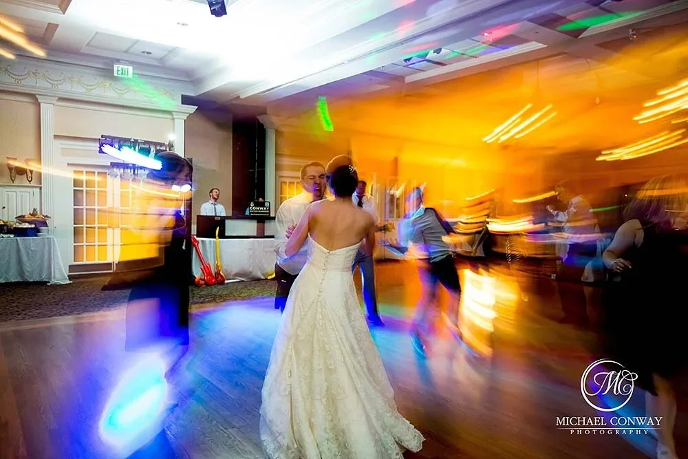 Couple dancing at a wedding reception with colorful lighting and motion blur effects.