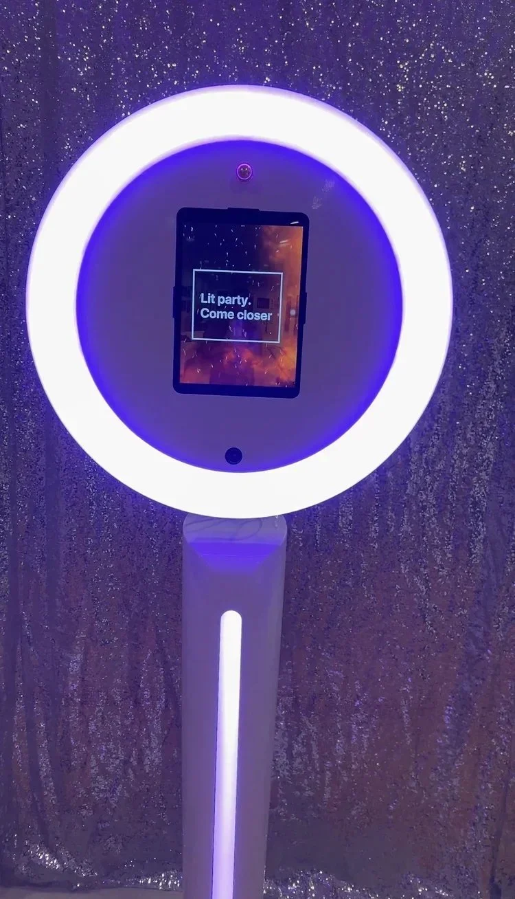 A glowing illuminated stand with a digital screen displaying 'Lit party. Come closer' against a sparkly, glittery backdrop.