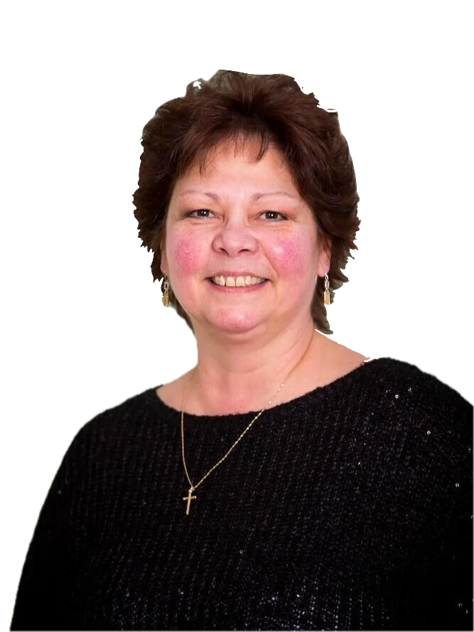 Portrait of a smiling middle-aged woman with short, wavy brown hair, wearing a black sweater and a gold cross necklace, against a plain background.