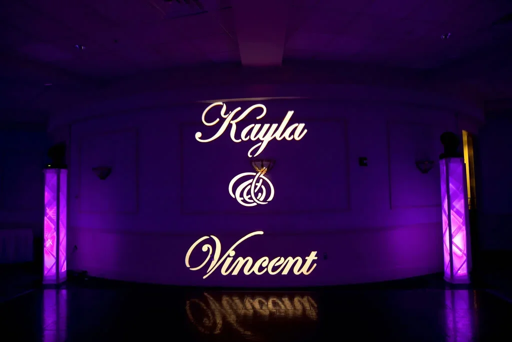 A purple-lit event wall displaying the names Kayla and Vincent with a knot design between them.