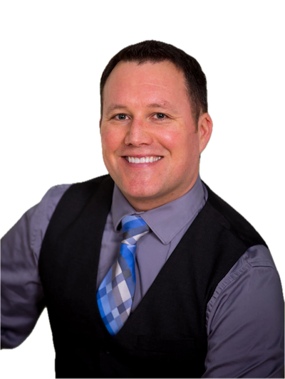 Smiling man in a gray shirt, blue and gray plaid tie, and black vest, against a plain background.