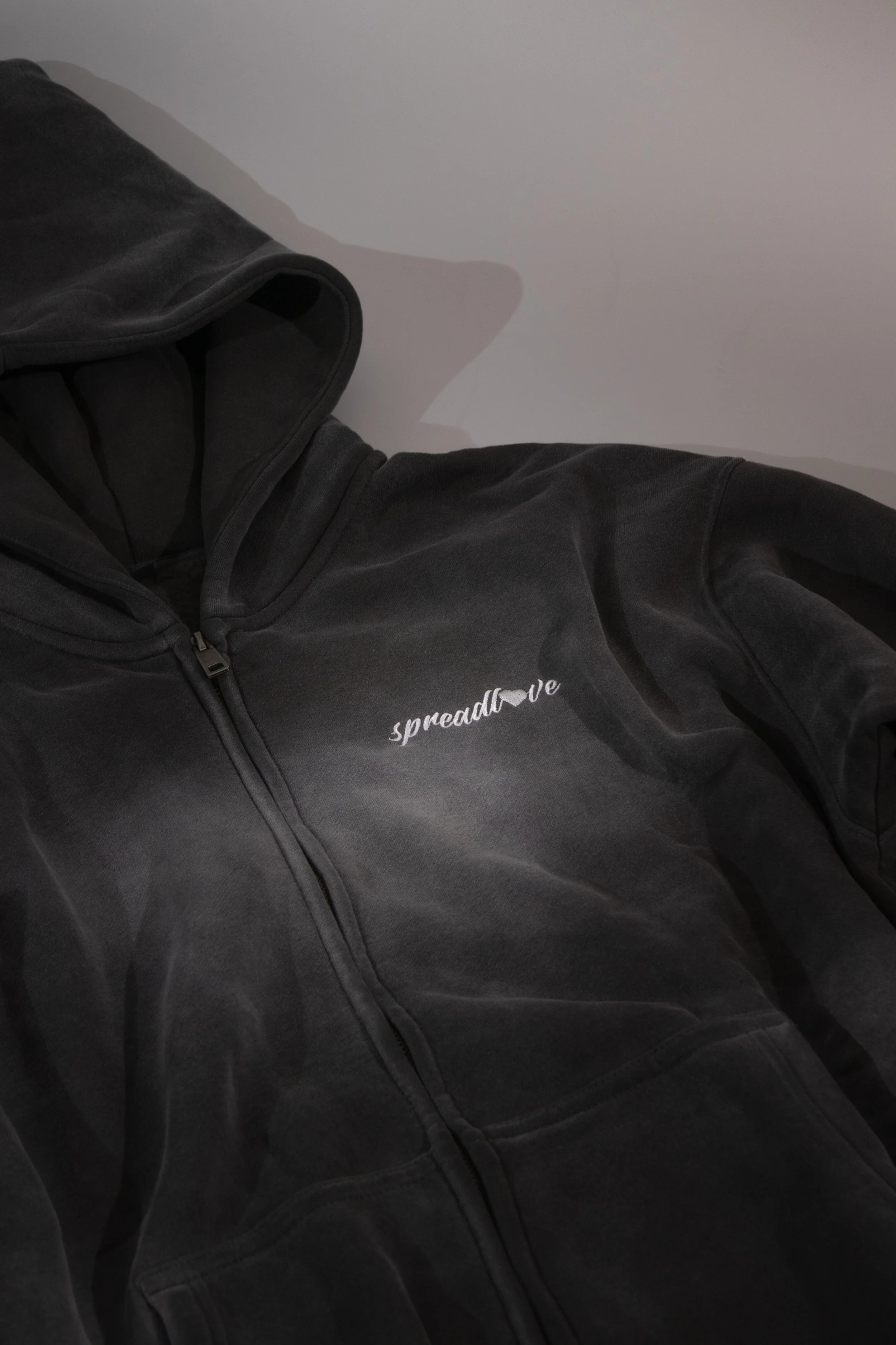 Veste à capuche noire avec le mot « spreadlove » écris en blanc sur la poitrine