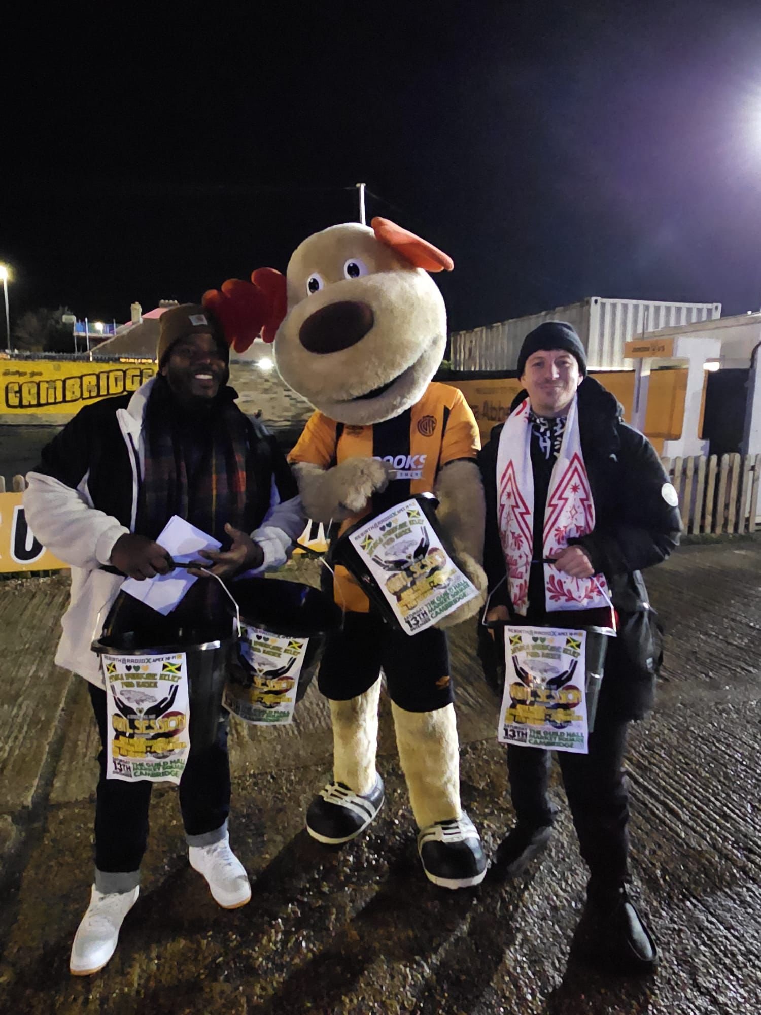 Community volunteers fundraising with a football club mascot, collecting donations to support Jamaica relief efforts after Hurricane Melissa