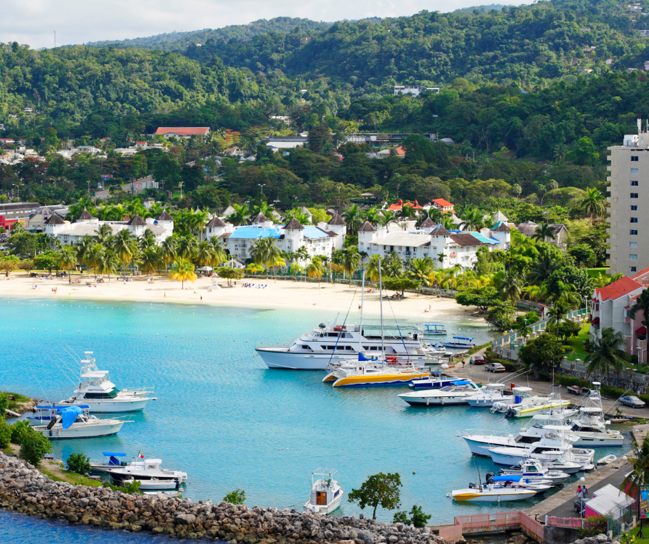 Coastal town and harbour in Jamaica showing homes, boats, and surrounding hills following Hurricane Melissa