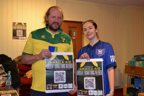 Norwich Jamaica Aid volunteers holding fundraising posters to support hurricane relief efforts in Jamaica
