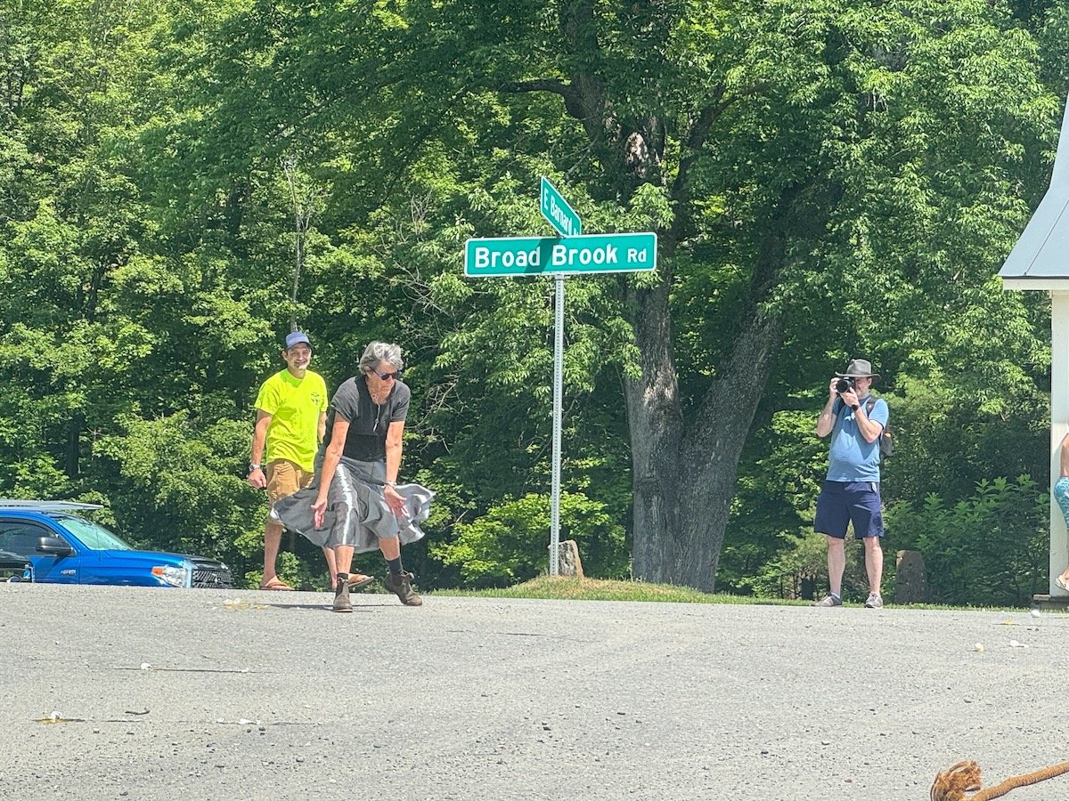People standing near a street sign that reads 'Broad Brook Rd' at the intersection of E Banner.