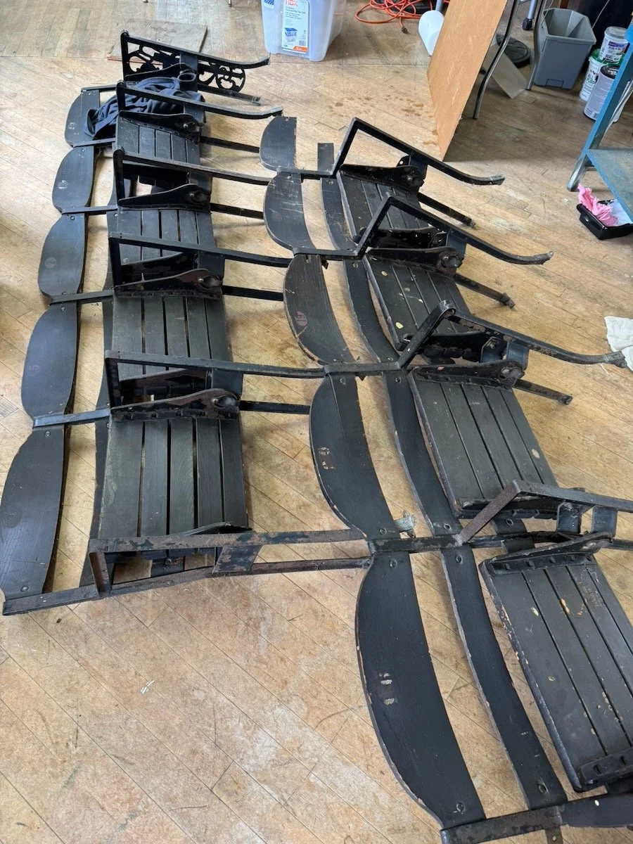 Collection of vintage wooden snowshoes with metal bindings, laid out on a wooden floor in a workshop.