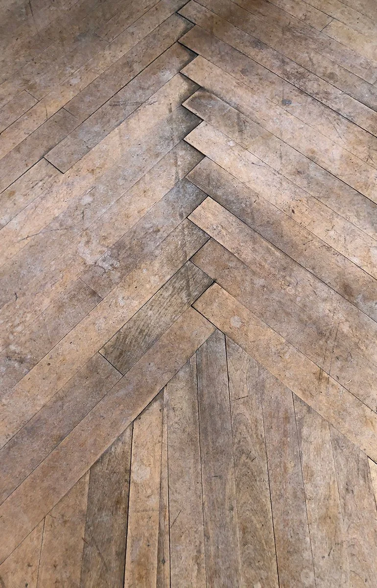 Close-up of a wooden herringbone patterned floor with a central angled inlay.