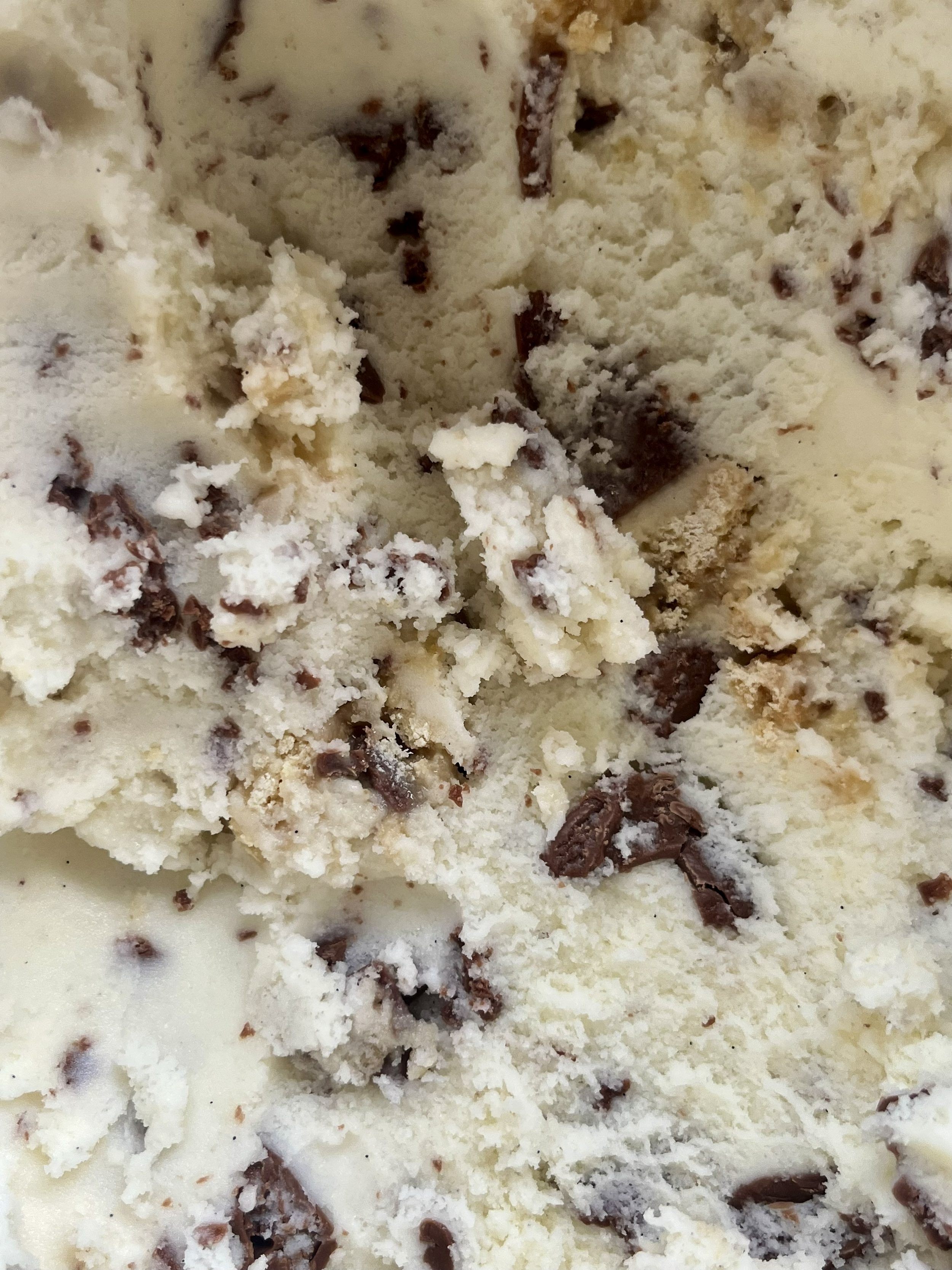 Close-up of vanilla ice cream with chocolate chunks, caramel and shortbread pieces.