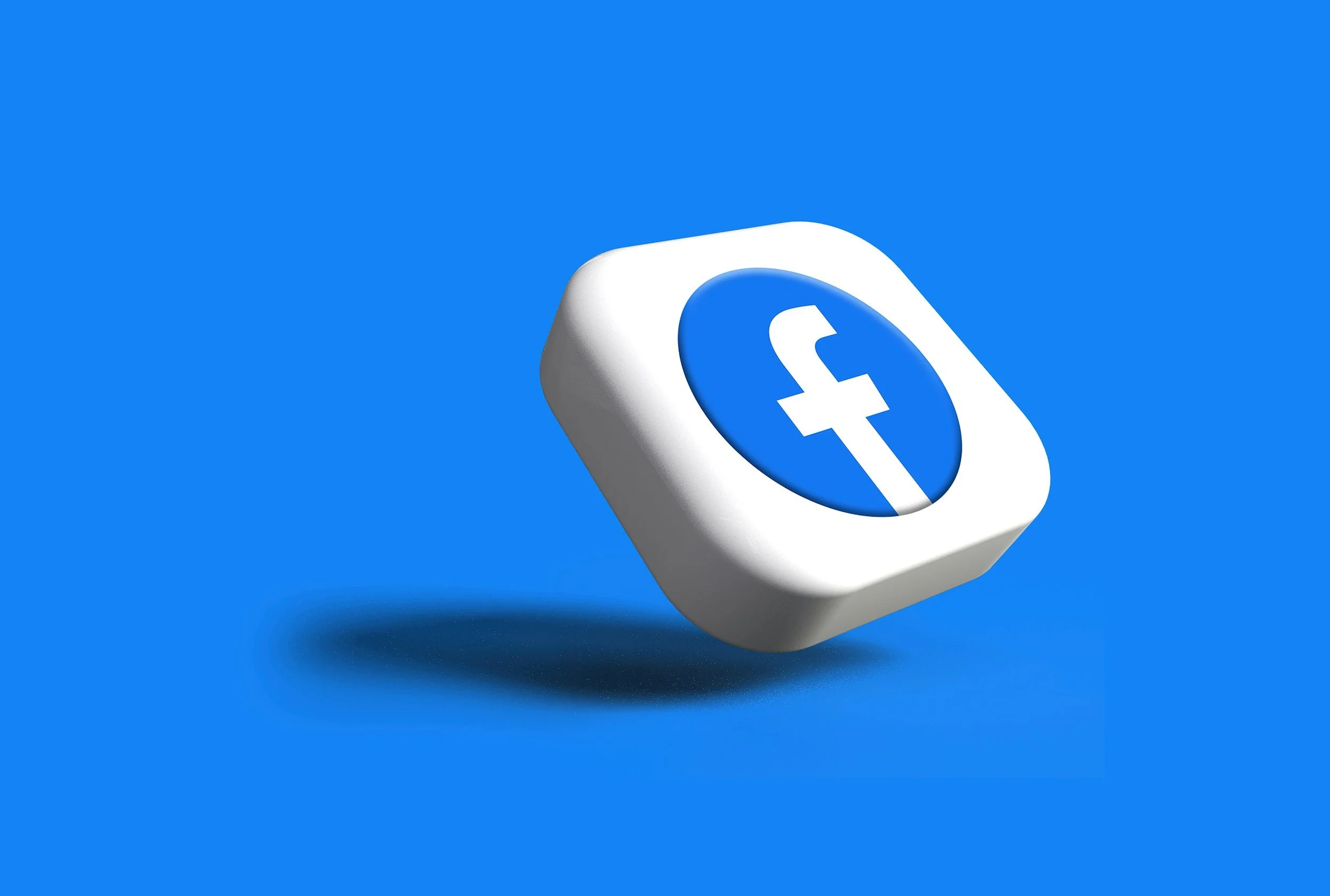 3D illustration of a floating white pill with the Facebook logo in the center, set against a solid blue background.