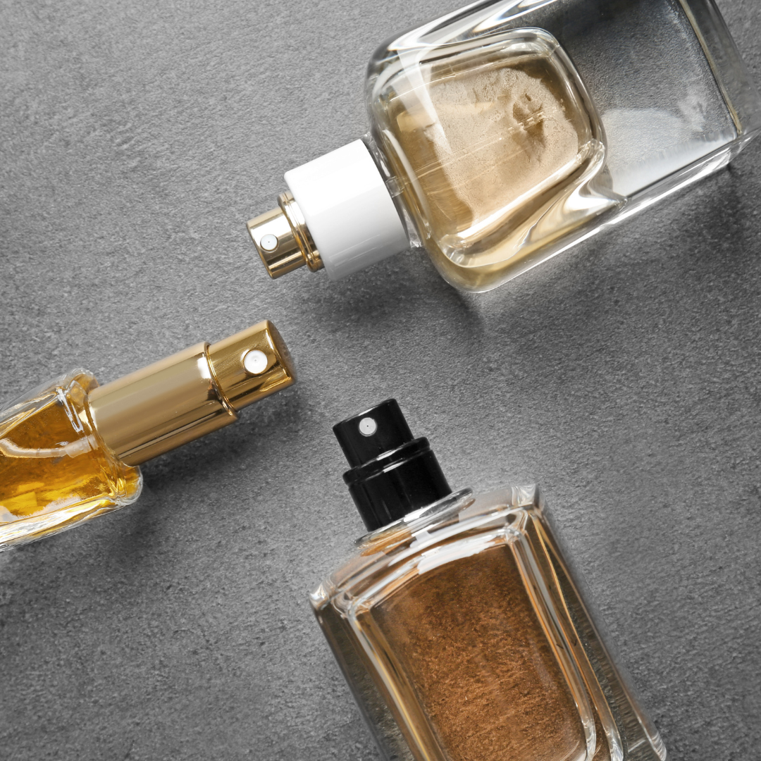 Three perfumes laying on a gray background.