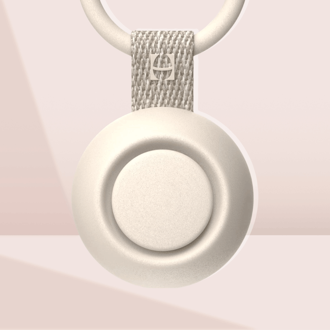 Hatch Go Portable Sound Machine for babies, featuring a compact cream-colored circular design with a silicone strap for travel convenience.