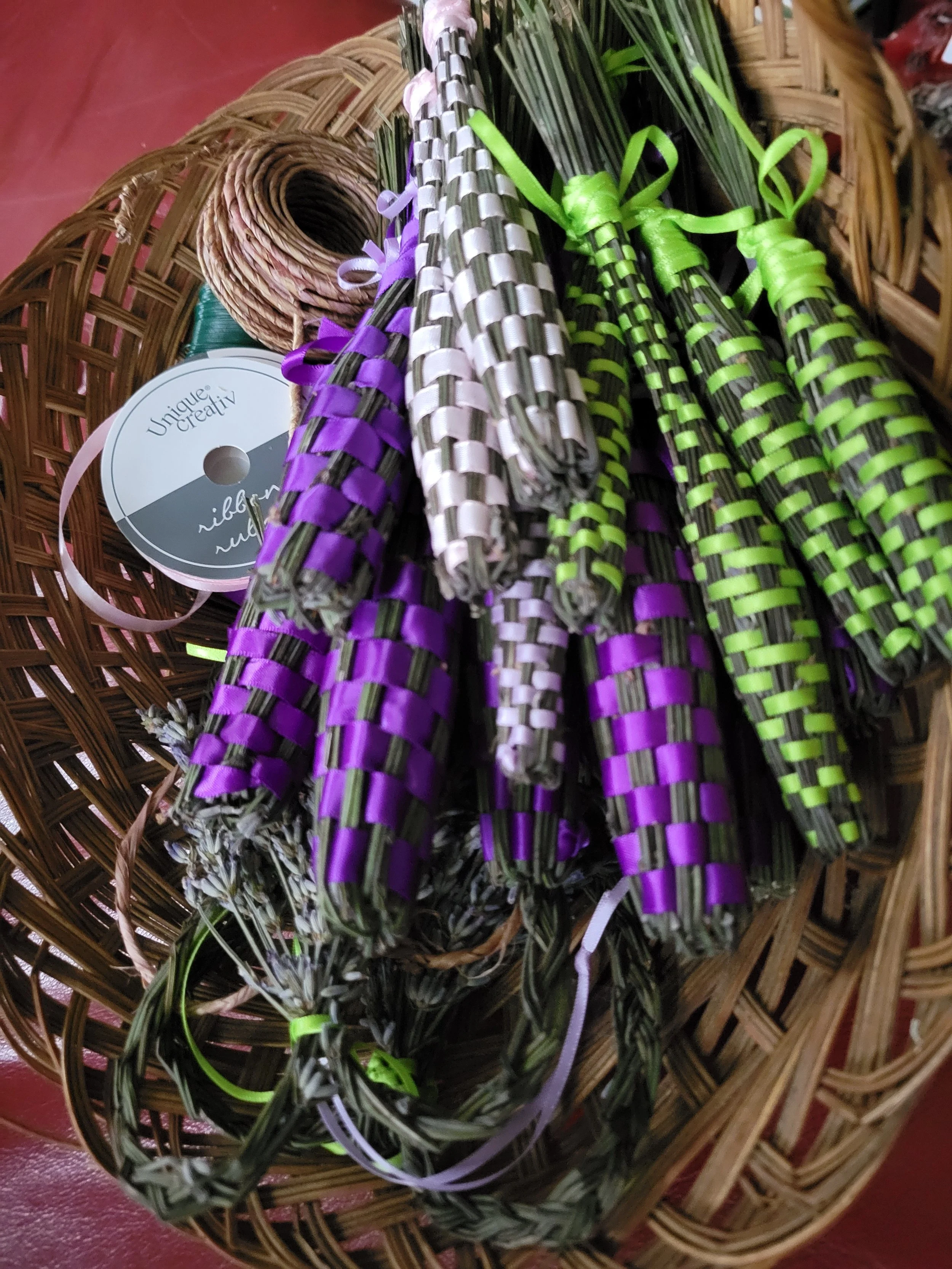 Decorative dried floral arrangement with green foliage, purple and silver ribbon, and woven baskets