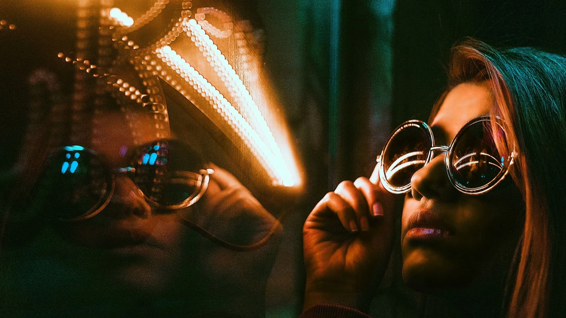 Jeune femme portant des lunettes rondes, regardant son reflet dans une vitre avec un néon lumineux, illustrant la méditation Regarder ses pensées pour débutants, pour observer ses pensées avec simplicité et bienveillance.