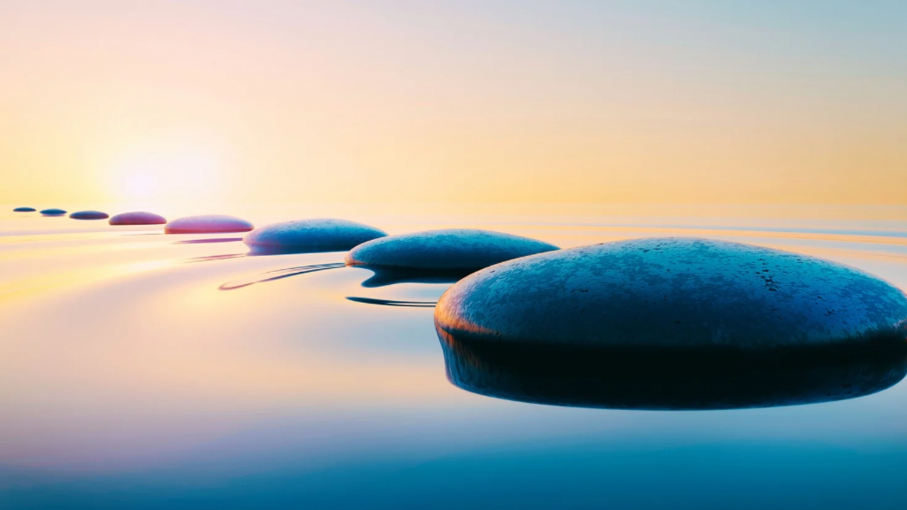 Méditation guidée pour apaiser rapidement l’anxiété et revenir au calme illustré par une image de roches dans l’eau représentant la stabilité au milieu du mouvement.