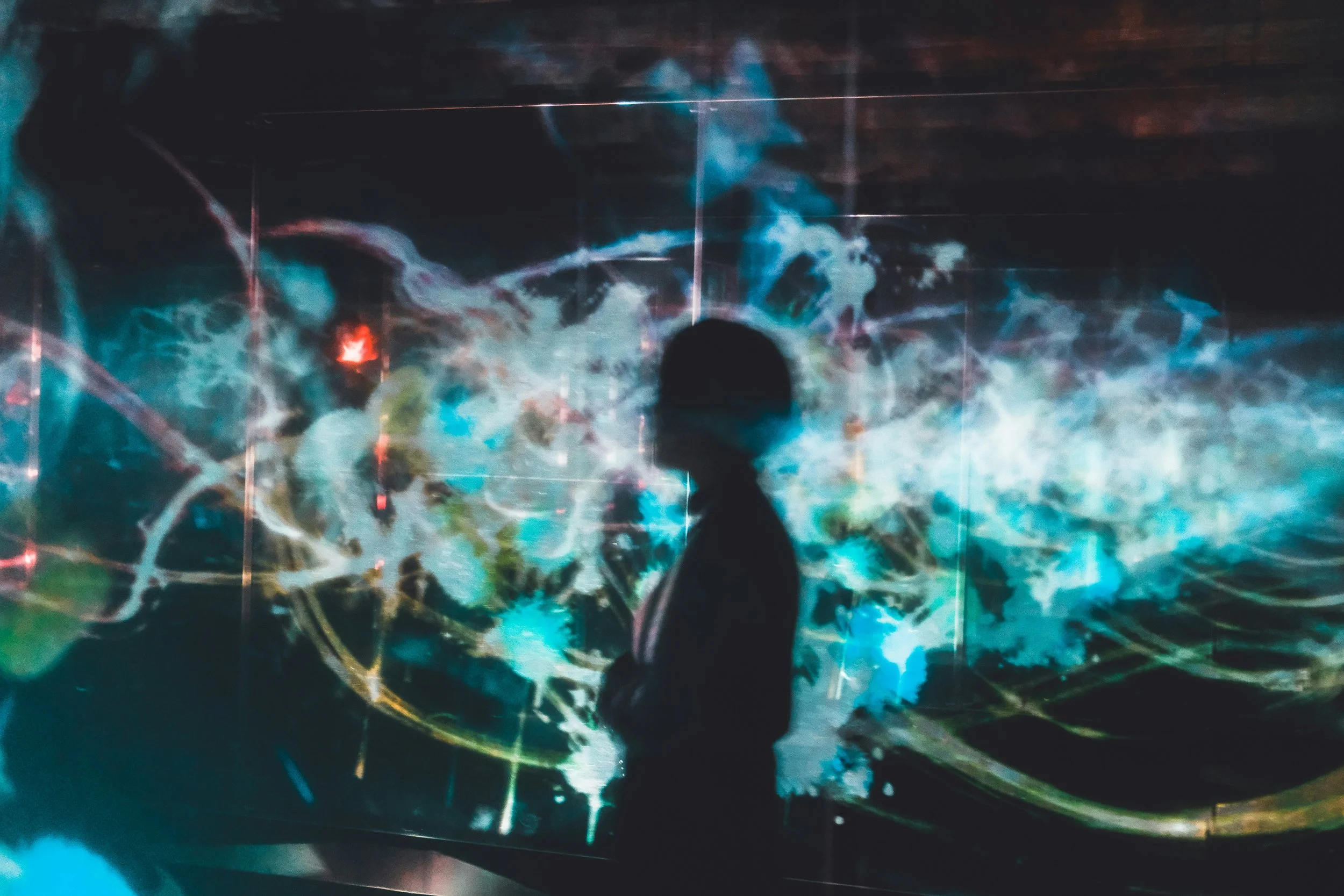 Silhouette de profil presque comme une ombre, entourée de fréquences visuelles teintées de bleu et de jaune sur fond sombre pour illustrer une méditation d’expérience sonore dans la page pour les visiteurs