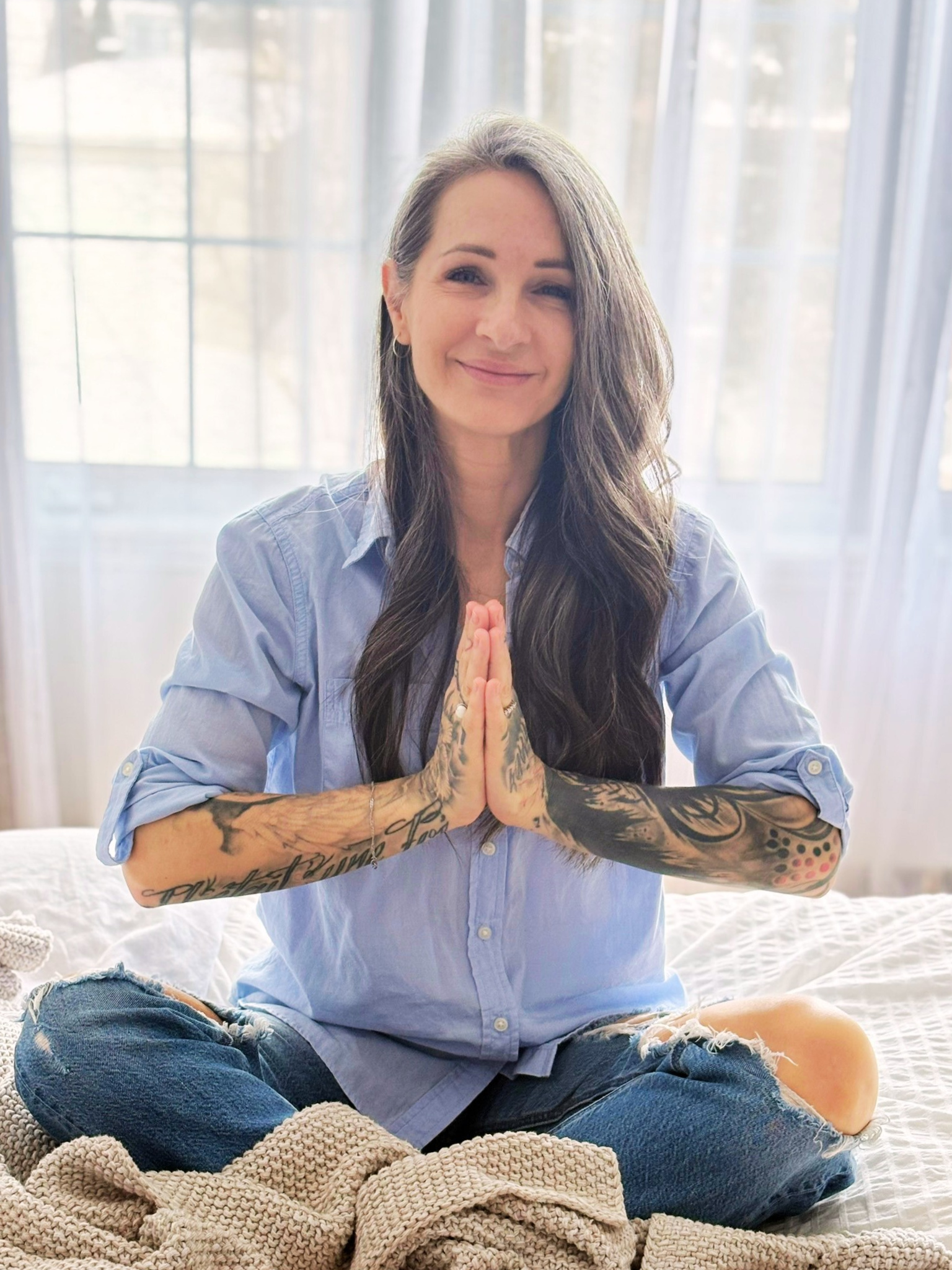 Isabelle Arnold la créatrice de izaamedit parfois écrit isamedite, assise en position de méditation mains en prière avec un sourire chaleureux.