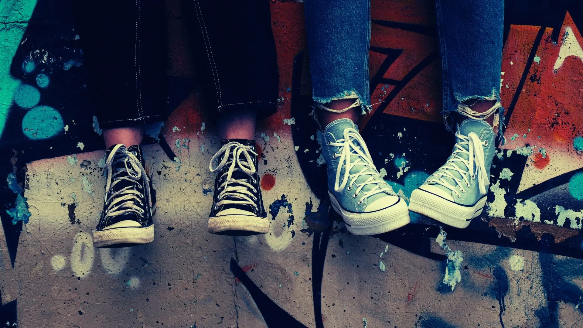 Bas des jambes de deux adolescents en jeans et running shoes Converse sur un mur graffité, illustrant la méditation Tu es assez pour adolescents, pour un espace sécurisé et soutenir l’estime de soi.