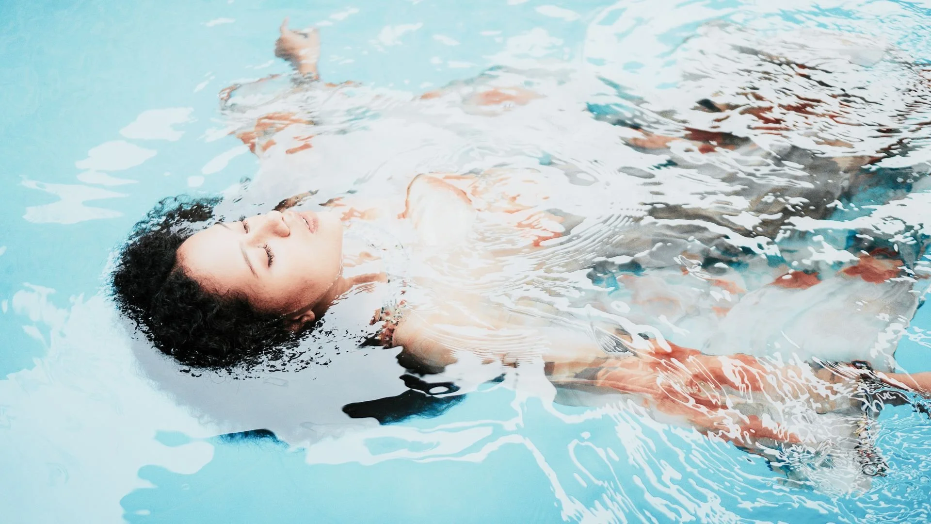 Femme flottant sur le dos dans une eau claire et lumineuse, illustrant une méditation guidée apaisante pour relâcher les tensions et retrouver calme et clarté intérieure.