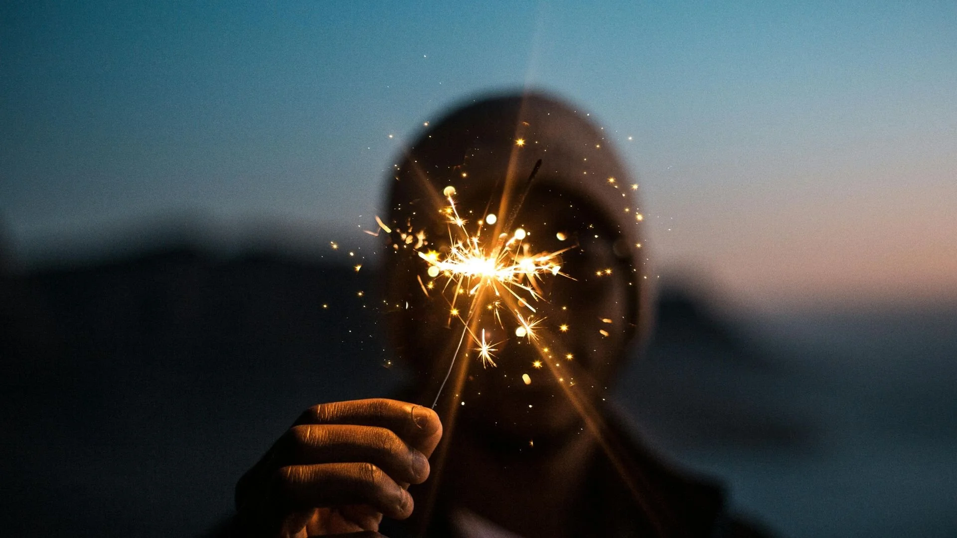 Personne légèrement floutée tenant une fil de fer avec flamme/flamèches lumineuse dans les mains, illustrant une méditation inspirante pour raviver l’énergie, la motivation et la confiance en soi.