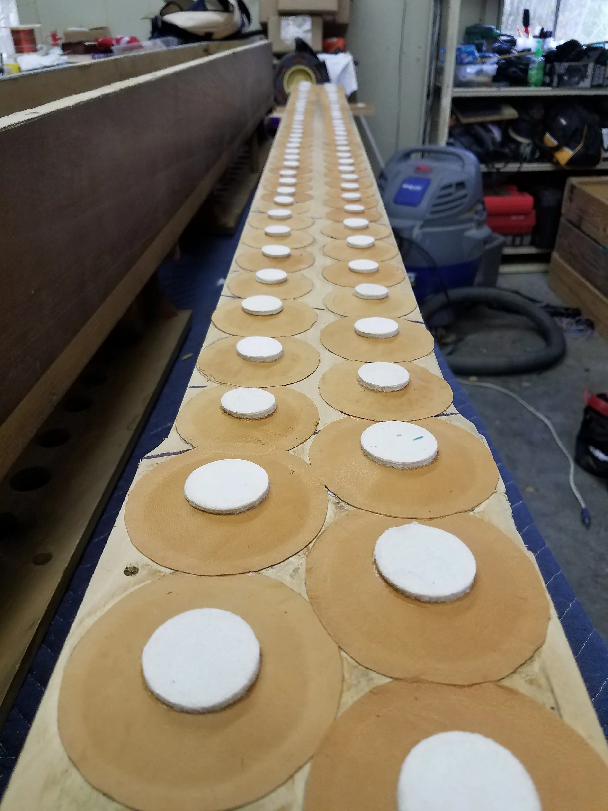 Row of skateboard decks with white circular grip tape pads in a workshop.